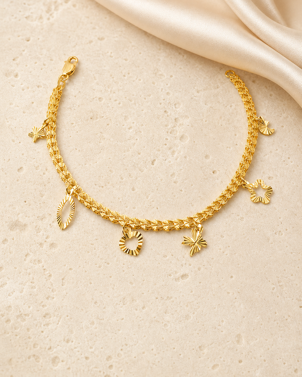 Gold charm bracelet styled on warm ivory stone