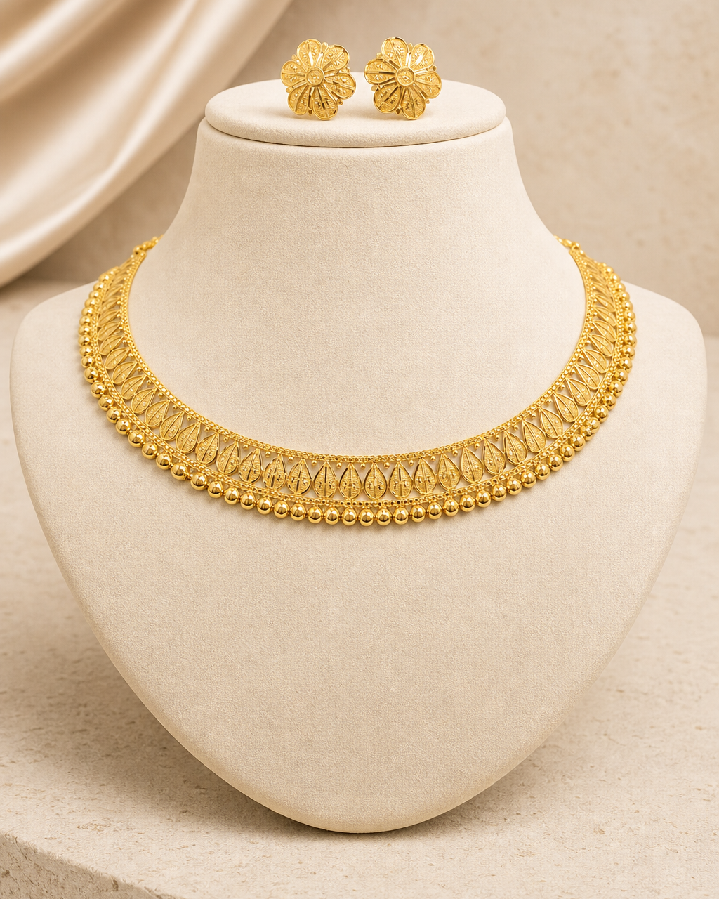 22ct gold leaf-motif necklace set on an ivory display bust