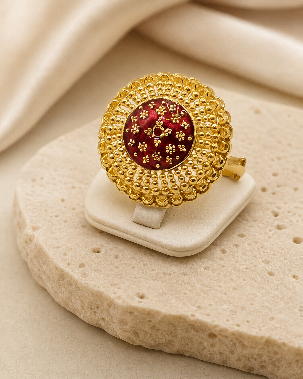 Ruby-red enamel gold cocktail ring on an ivory stand